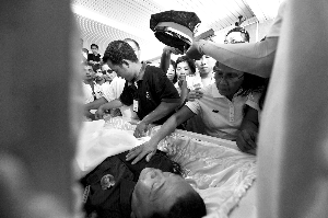 28日，兇手門多薩身著警服躺在棺木里。