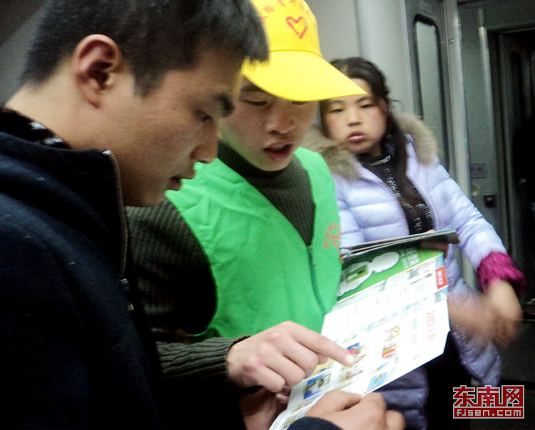 志愿者在列車上發(fā)放宣傳手冊(cè)(通訊員丁輝攝)