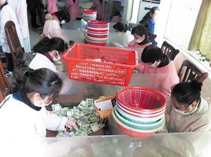 點鈔員們在低頭緊張地工作，她們每人每天都需要點鈔25箱1萬元以上。 陳暄 攝