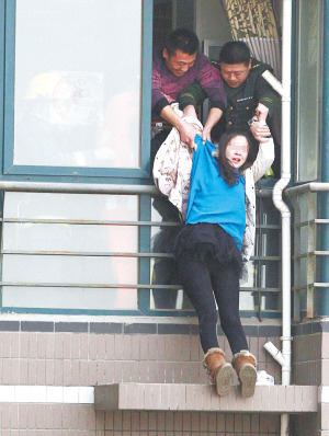 年輕女子在高樓窗外一小平臺(tái)坐了1個(gè)多小時(shí)后，被消防官兵拉進(jìn)屋內(nèi)。