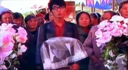 何濱捧著愛人遺像，送上深情一吻。（視頻截圖）