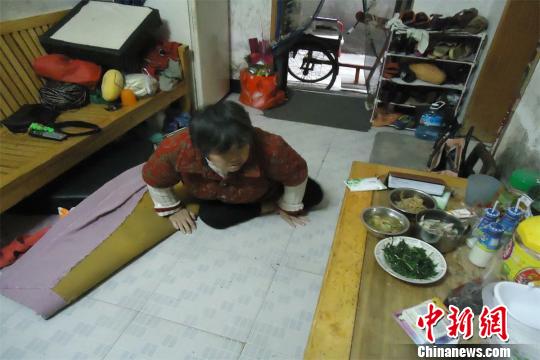 17日下午，56歲小兒麻痹癥患者張紅英爬在地板上找東西。 蘇路程 攝