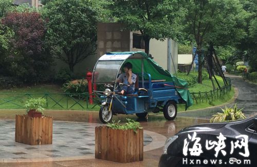 這名快遞哥騎行在小區(qū)通道內(nèi)，一邊接打手機(jī)，一邊還把腳架在車前欄桿上